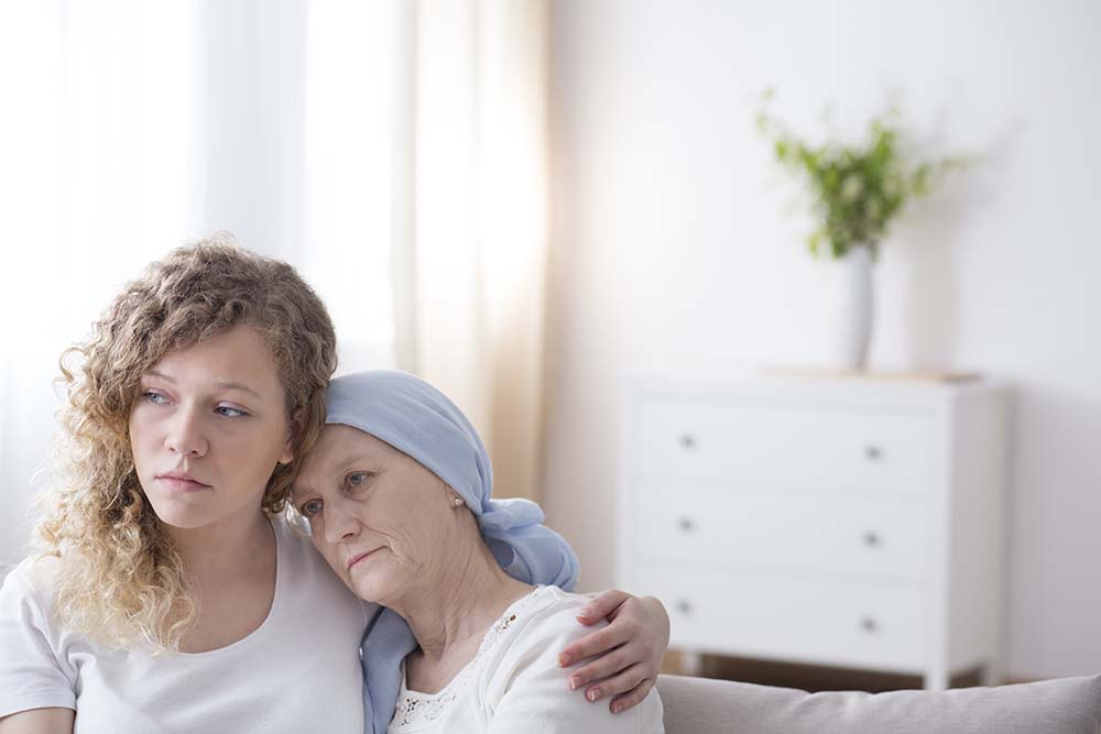 vrouw met hoofddoek leunt op schouder van dochter met krulharen