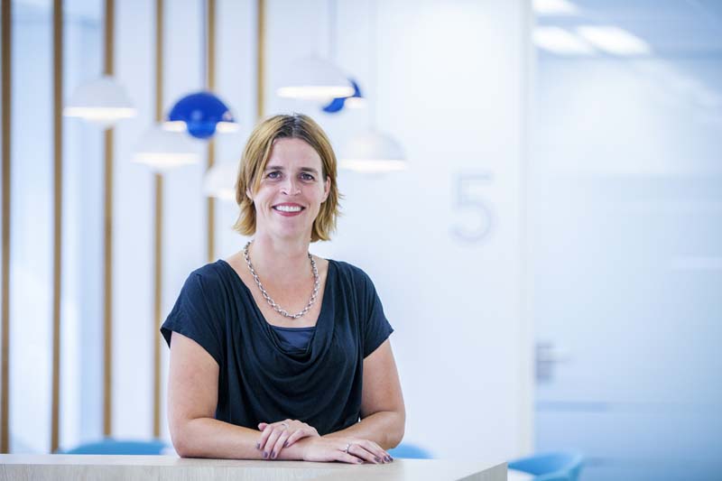 Karin staat glimlachend aan de receptiedesk van het IKNL-kantoor in Utrecht.